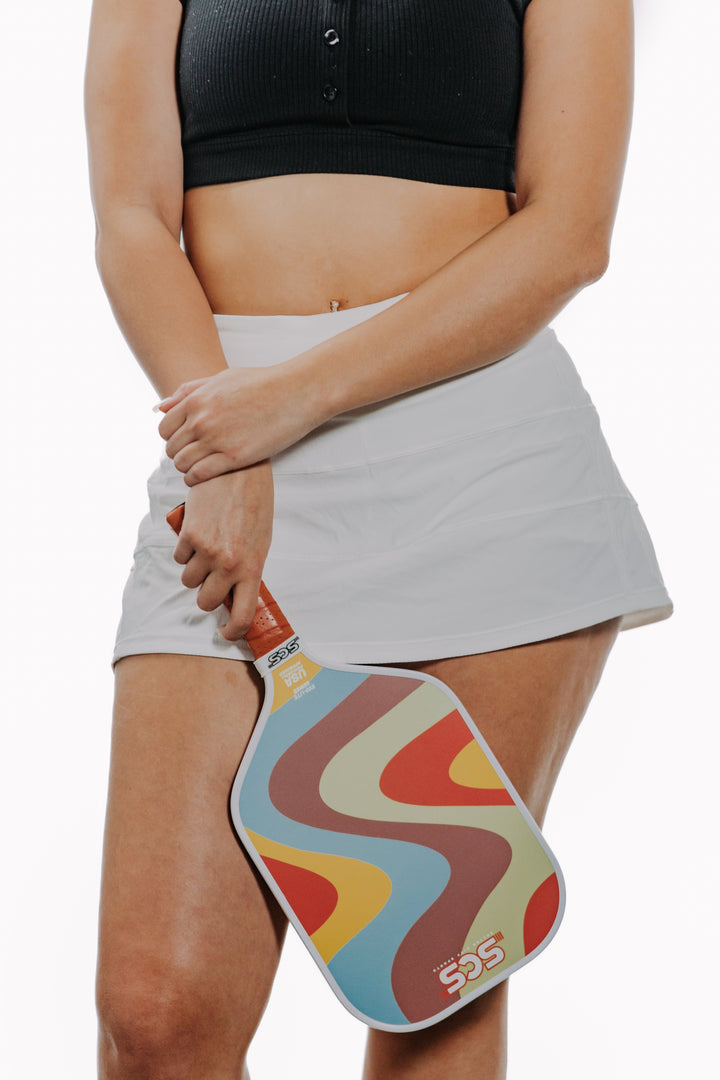 Person holding a colorful paddle with a white background.
