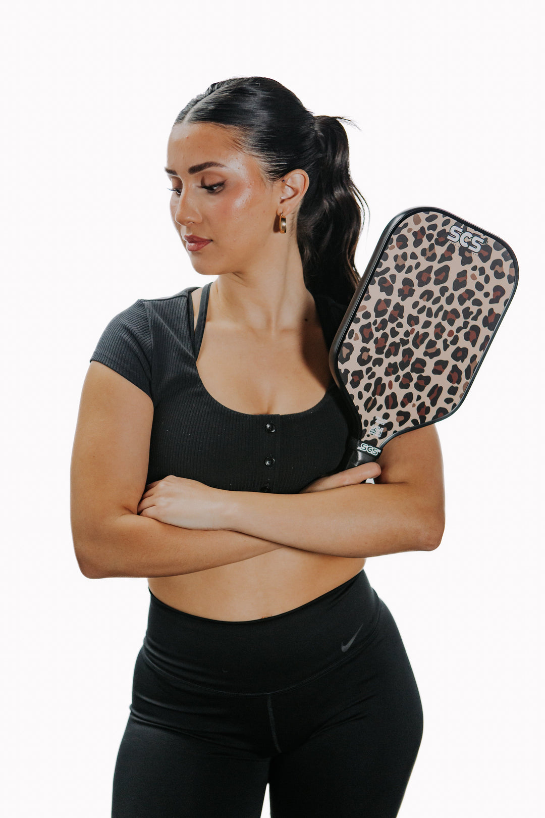 Woman holding a leopard print pickleball paddle against a white background.