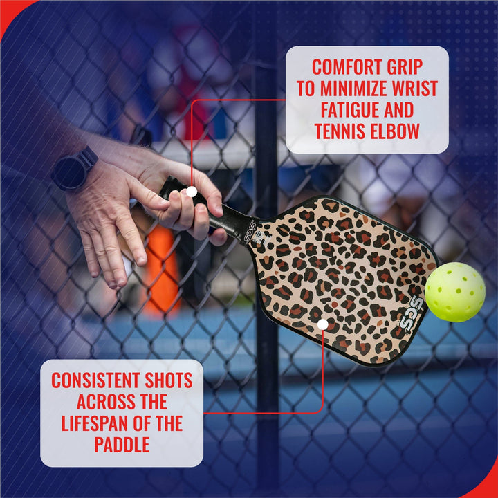 Leopard print pickleball paddle with text on comfort grip and shot consistency, against a blurred outdoor background.