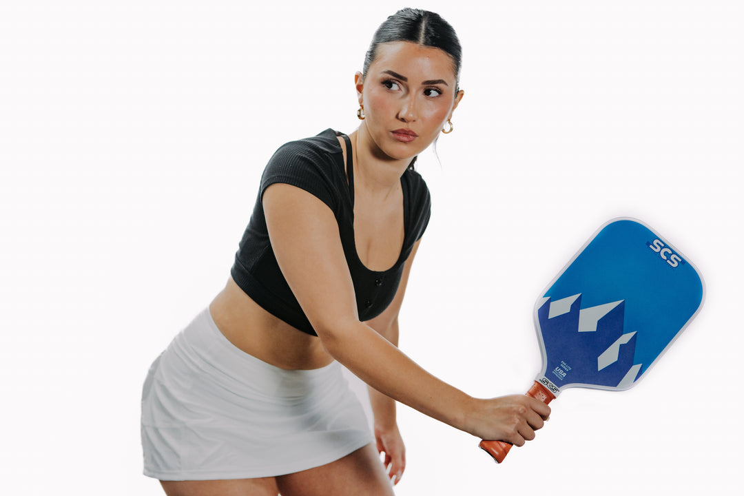 Woman holding a blue pickleball paddle on a white background.