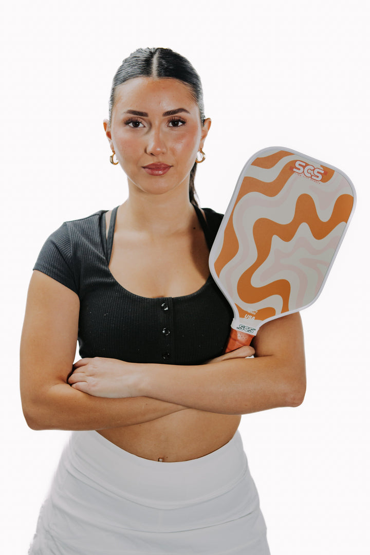 Woman holding a paddle with a white and orange design on a white background.