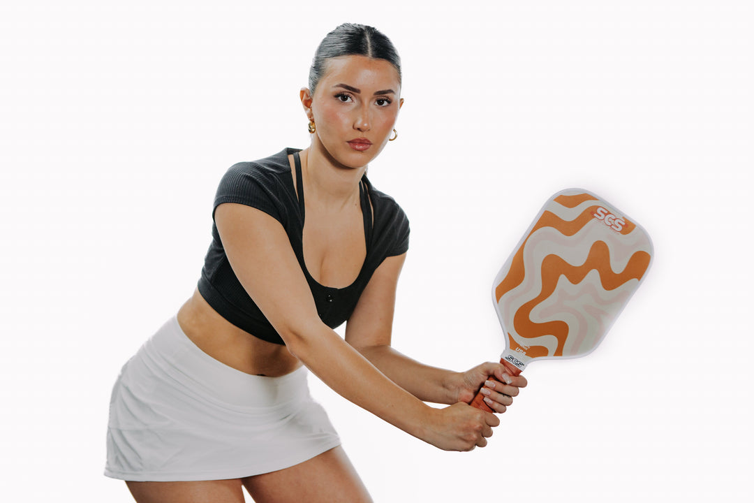 Woman holding a pickleball paddle on a white background.