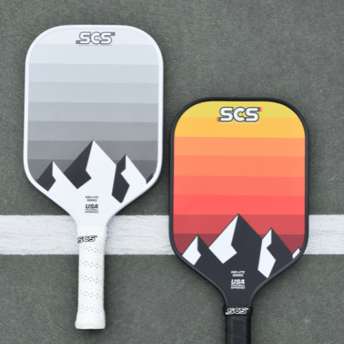 Two pickleball paddles with mountain designs on a gray background.