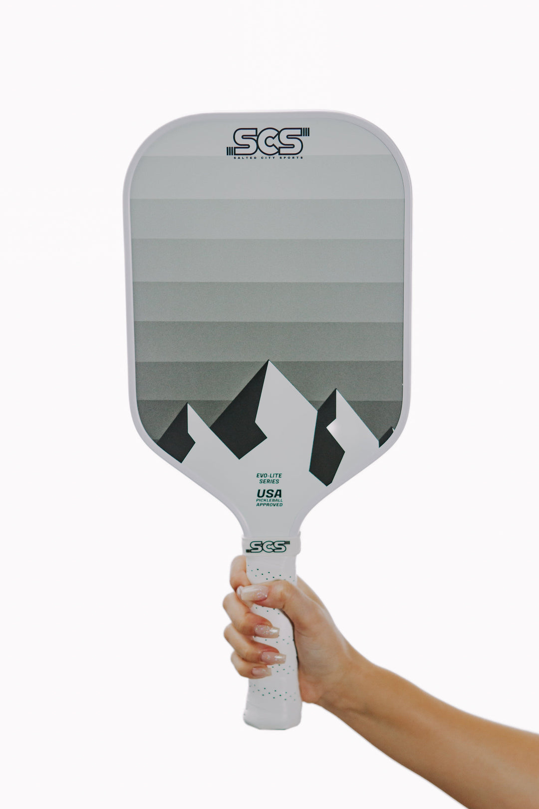 Gray pickleball paddle with a mountain design held by a hand on a white background.