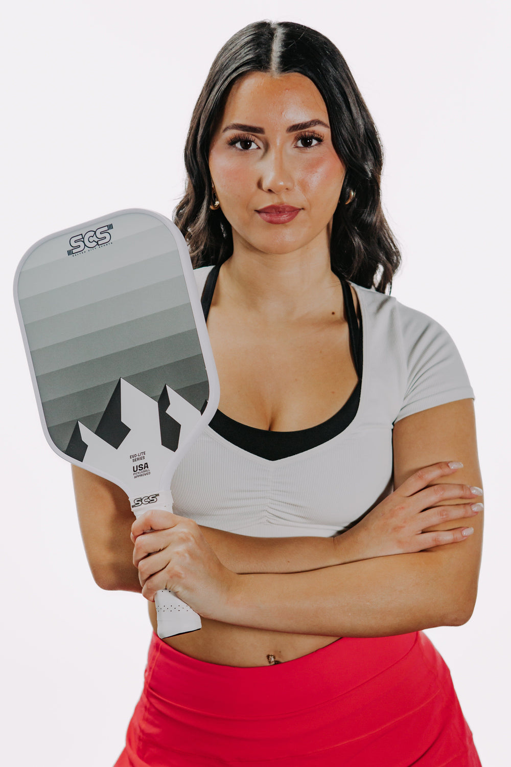 Woman holding a pickleball paddle with a white background.