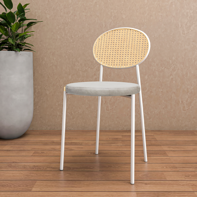 Chair with wicker backrest and white frame on wooden floor against beige wall.