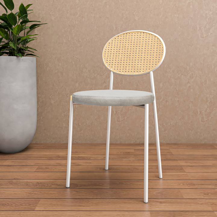 Chair with wicker backrest and white frame on wooden floor against beige wall.