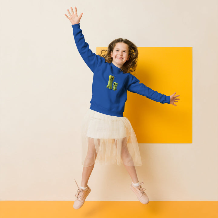 Child wearing a blue sweatshirt with a green graphic and white skirt, jumping against a yellow background.