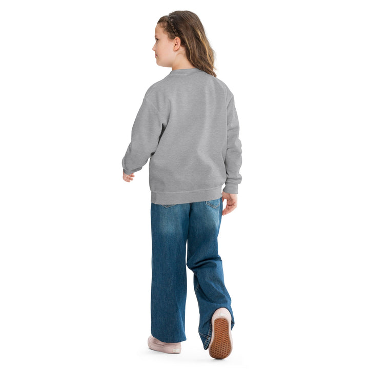 Child wearing a gray sweatshirt and blue jeans on a white background.